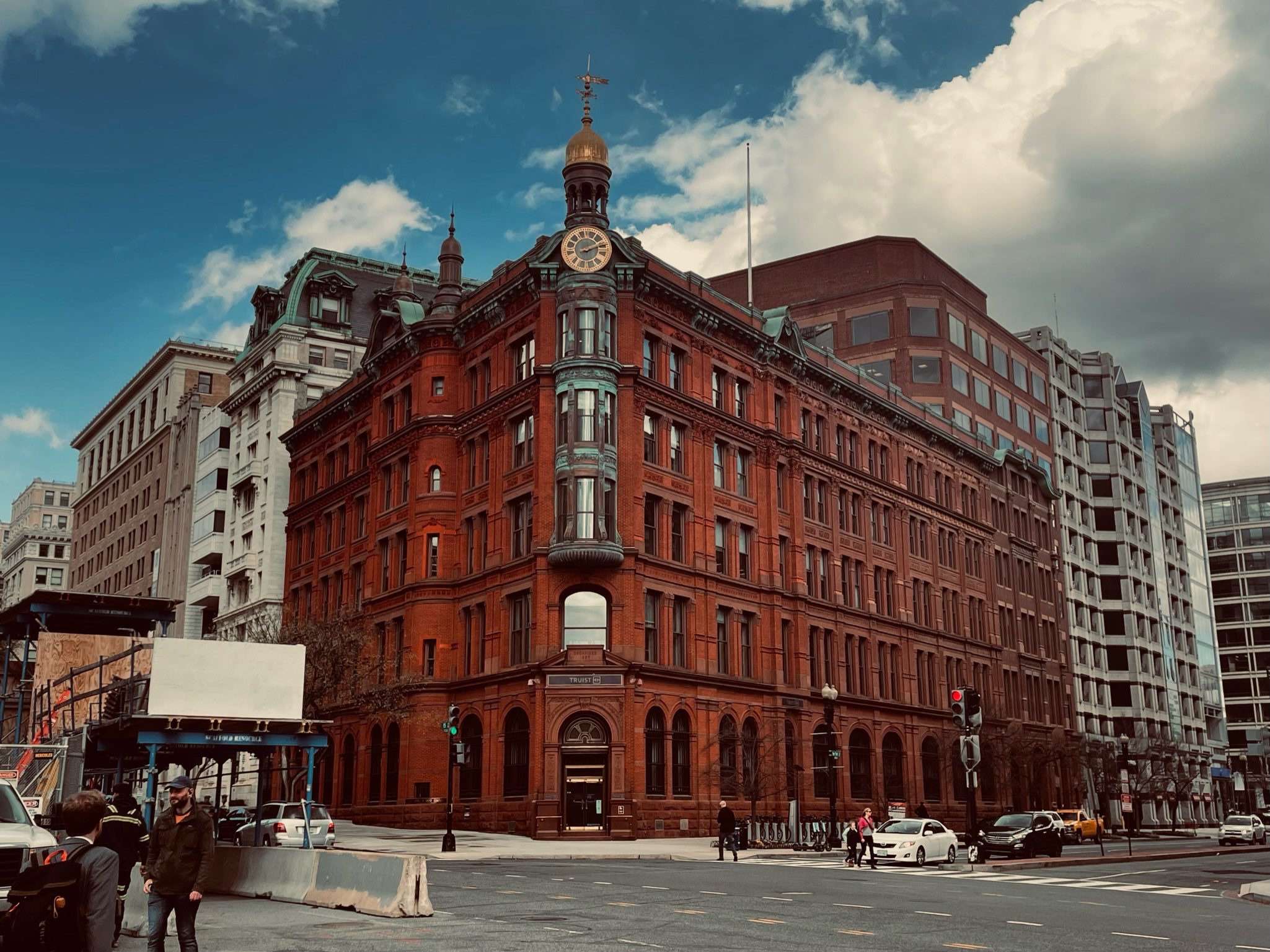 A red-brick Victorian building with a clock tower on a city street corner